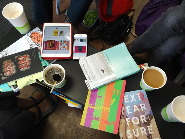 Table, books, coffee and readers' legs and shoes visible at first Toronto silent book club meeting