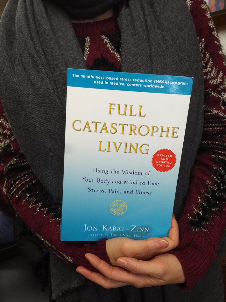 Silent book club participant holds the book Full Catastrophe Living by Jon Kabat-Zinn