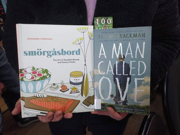 Silent book club participant holds the books Smorgasbord by Johanna Kindvall and A Man Called Ove by Fredrick Backman