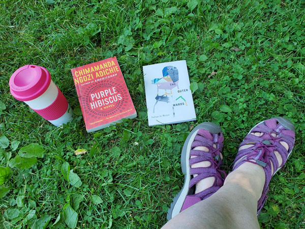 Silent book club member's feet next to her books and beverage