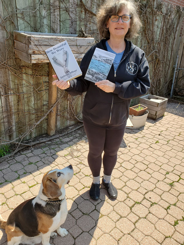 Vicki with books and Jake the beagle-basset in the backyard