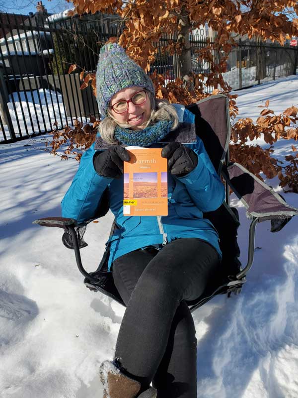 Silent book club member Catherine sitting in a chair in snowy Stephenson Park, holding a book by David Sherrell