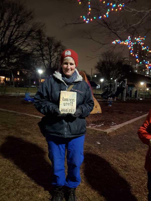 Silent book club member Sue in the park, with a book by Lauren Groff