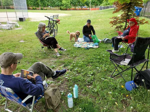 Silent book club members in the park with books