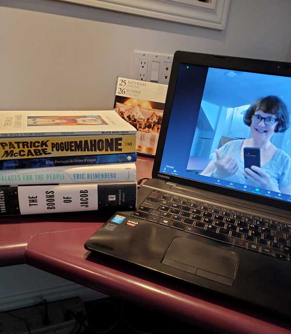 Vicki on screen, getting reading for the zoom silent book club meeting, with her books stacked next to her computer