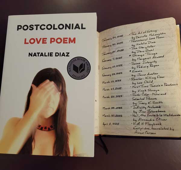 My 2022 year in reading, reflected in a page of my handwritten Book of Books, next to the poetry collection Postcolonial Love Poem by Natalie Diaz