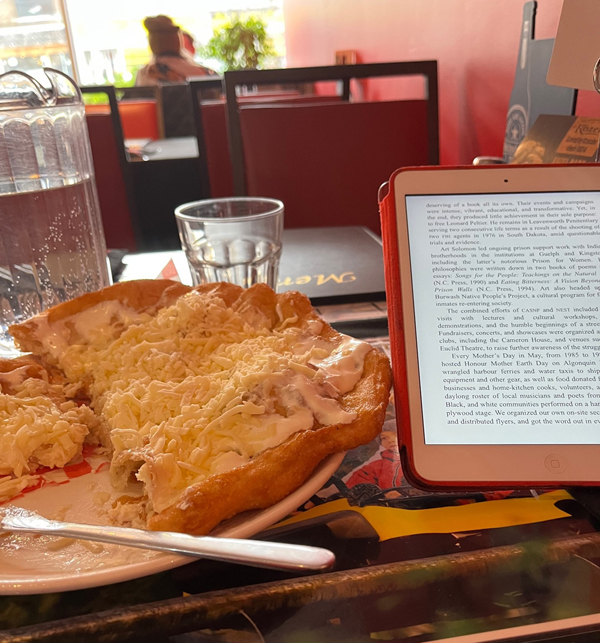 Silent book club members Jo and Philippa met in person at the restaurant Budapest on the Danforth in east end Toronto and read silent together. A pastry sits on a plate next to an ebook reader.