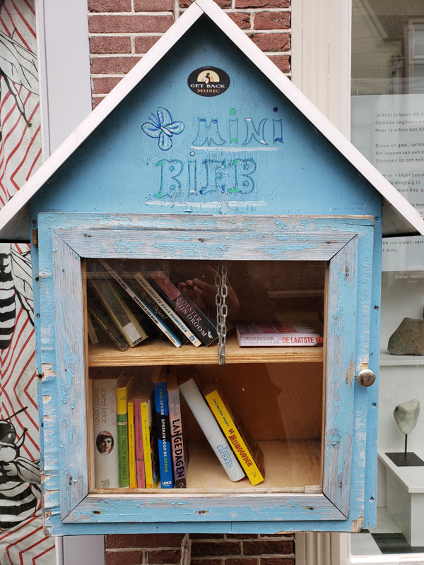 During her trip to Dordrecht, Netherlands, silent book club member Beth encountered this charming little library box, light blue paint a bit faded, a peaked roof, two bookshelves