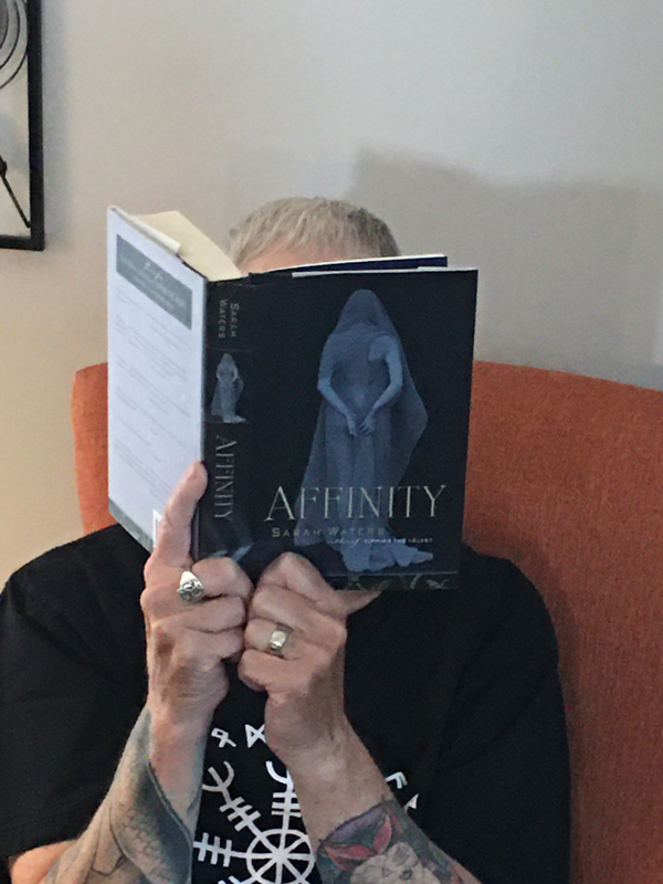 Silent book club member Sue reads Affinity by Sarah Waters, holding the book up to hide her face