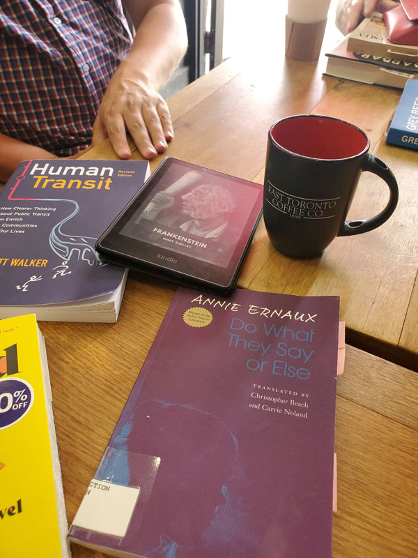 At East Toronto Coffee Co, getting ready for a silent book club meeting, with books by Jarrett Walker, Mary Shelley and Annie Ernaux on the wooden table, along with refreshments