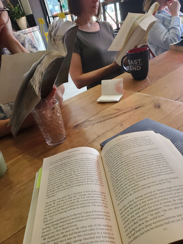 Silent book club readers with their books open at the table at East Toronto Coffee Co