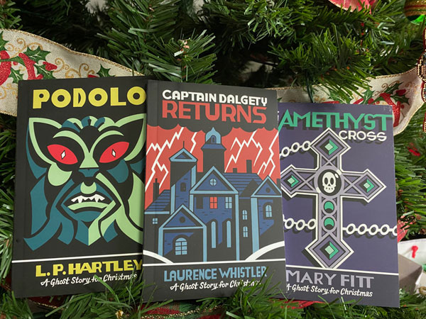 Silent book club member Jenn C read the Biblioasis Christmas Ghost Stories 2024: Podolo by L.P. Hartley, Captain Dalgety Returns by Laurence Whistler, Amethyst Cross by Mary Fitt. The wee books are arranged on a Christmas tree branch.