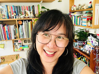 Silent book club member Joylyn Chai, smiling brightly with glorious bookshelves in the background