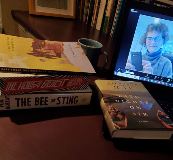 Me (Vicki), on-screen, getting ready for the silent book club zoom meeting, with my books piled next to the laptop, including Late Nights on Air by Elizabeth Hay