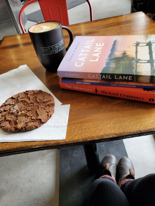 My (Vicki's) book pile at East Toronto Coffee Co, accompanied by coffee and ginger cookie: Cattail Lane by Fran Kimmel, Lost Signal by Chris Hutchinson and The Adversary by Michael Crummey