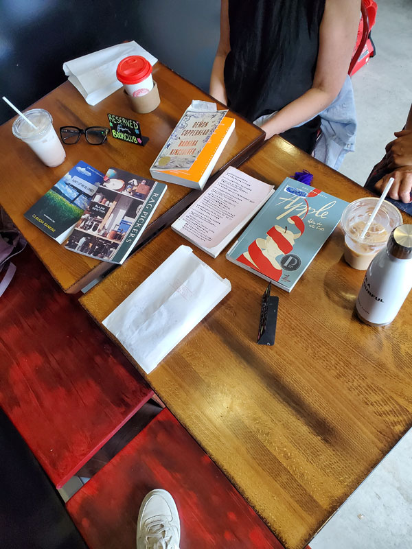 Group book pile at East Toronto Coffee Co, accompanied by coffees, cookies and pastries
