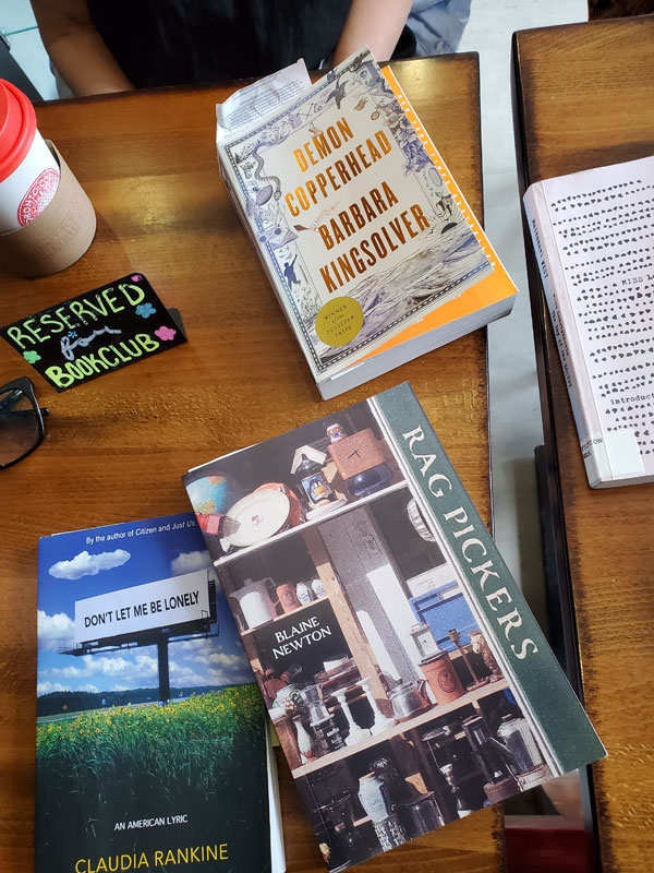 Group book pile at East Toronto Coffee Co, accompanied by coffees, cookies and pastries