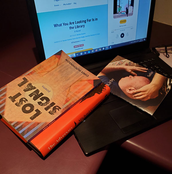 My (Vicki's) book pile: Lost Signal by Chris Hutchinson, The Adversary by Michael Crummey, Softie by Kirby, with the audiobook What You Are Looking For Is in the Library by Michiko Aoyama on my computer screen