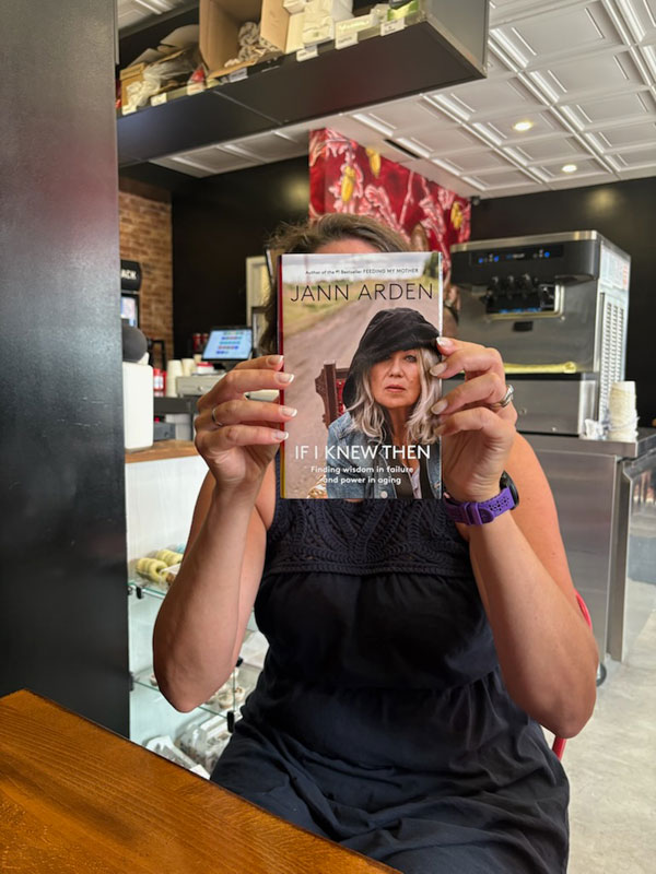 Book club member holds up the book If I Knew Then: Finding Wisdom in Failure and Power in Aging by Jann Arden - Photo by Jennifer D. Foster