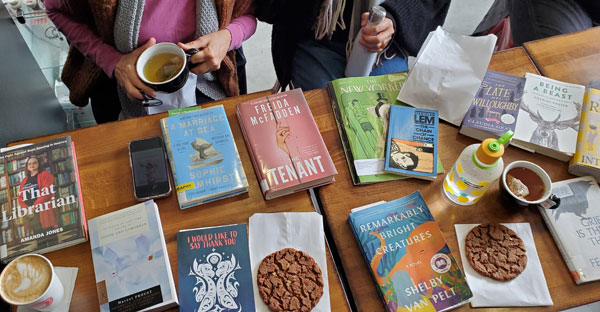 Group book pile at East Toronto Coffee Co, accompanied by coffee and pastries (Photo by Vicki Ziegler)