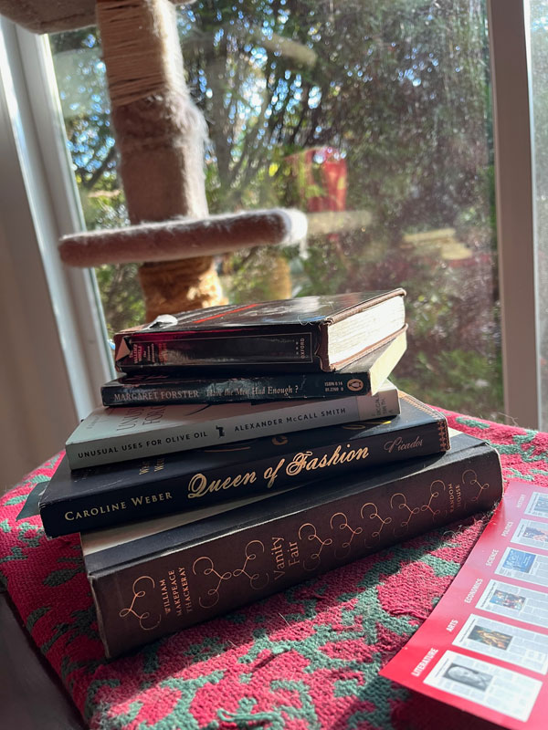 Silent book club member Helen's stack of books, next to a cat pole, including Vanity Fair by Thackeray (Photo by Helen Gunnarsson)