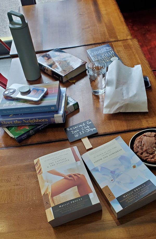 Group book pile at East Toronto Coffee Co, accompanied by coffee and pastries (Photo by Vicki Ziegler)