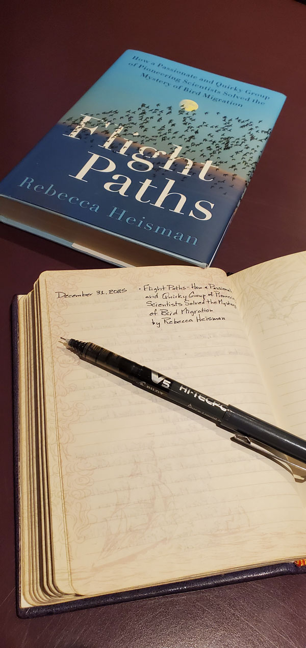 The book Flight Paths by Rebecca Heisman sits next to a notebook in which the book title is written.