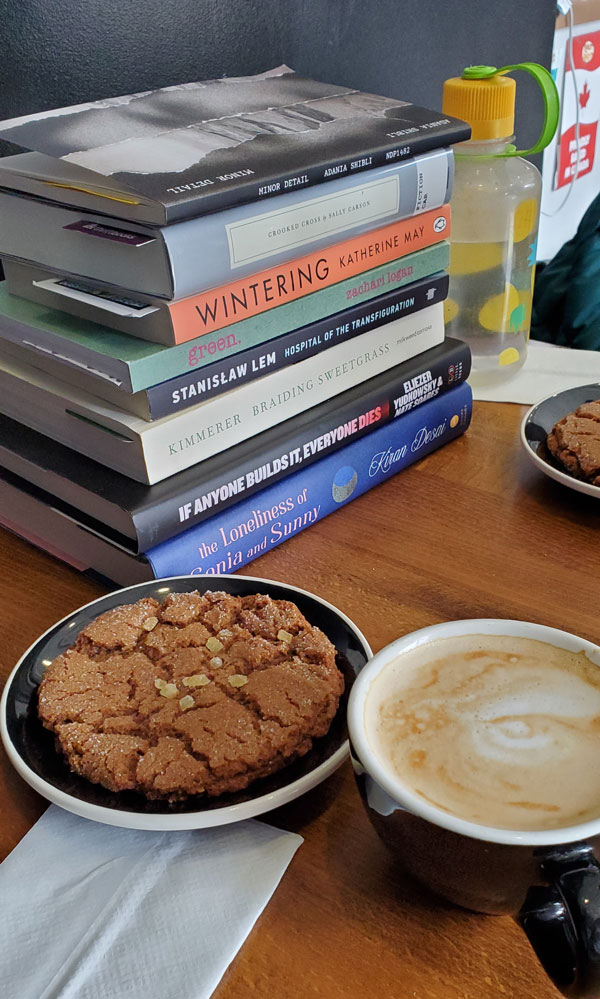Group book pile at East Toronto Coffee Co, including titles by Katherine May, Stanislaw Lem, Kiran Desai + more (Photo by Vicki Ziegler)