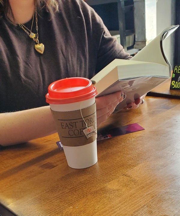 Reader reading at East Toronto Coffee Co, accompanied by coffee (Photo by Vicki Ziegler)
