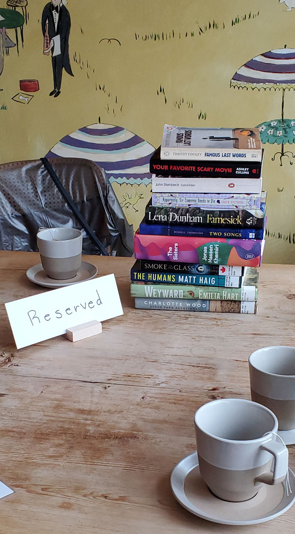 Towering pile of the collected books being read by east end Toronto silent book club members at the meeting at Paper Route Cafe (Photo by Vicki Ziegler)