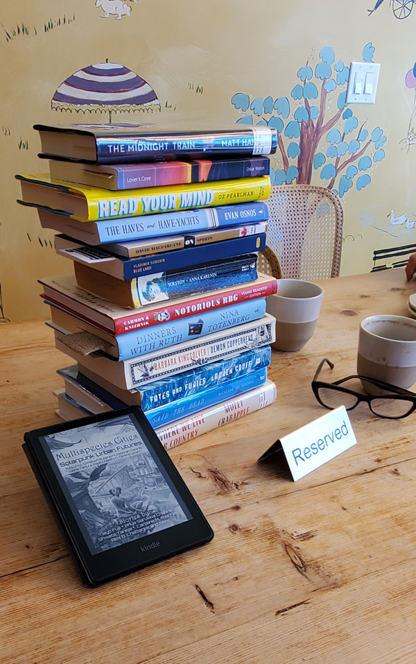 Teetering book pile at silent book club meeting at Paper Route Cafe  (Photo by Vicki Ziegler)