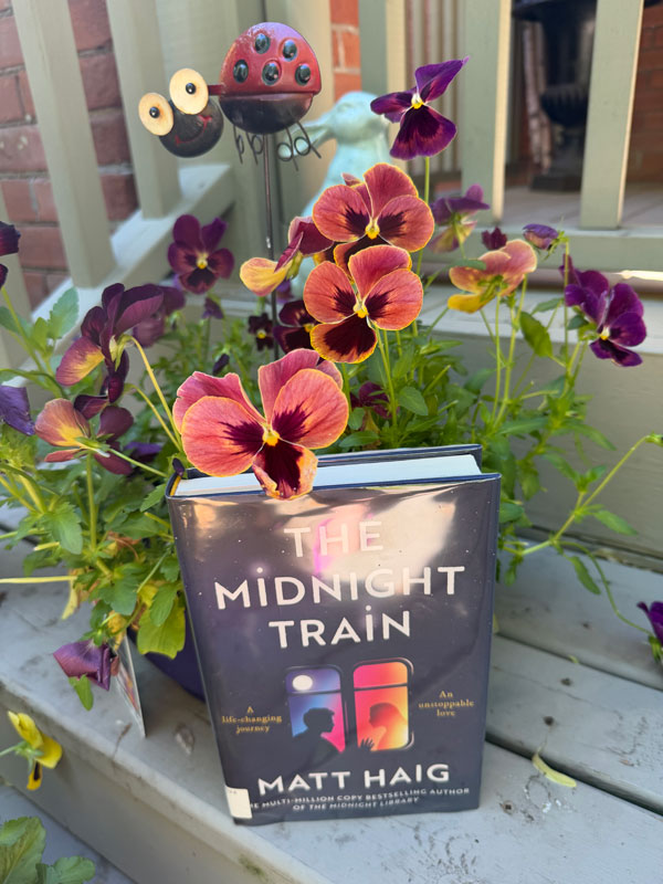 Silent book club member Jen places her reading, The Midnight Train by Matt Haig, next to some lovely flowers on her steps (Photo by Jen Foster)
