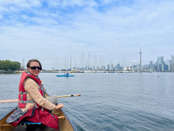 Silent book club member Jess smiles from her canoe, in sight of Toronto's CN Tower (Photo by Jess Bootsma)