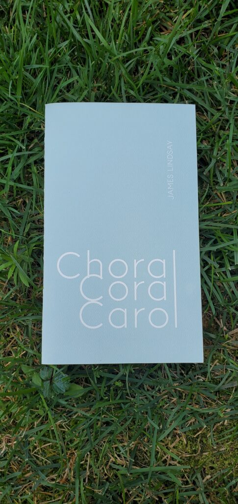 Poetry chapbook Choral Coral Carol by James Lindsay (2026 Knife Fork Book) sits in the grass