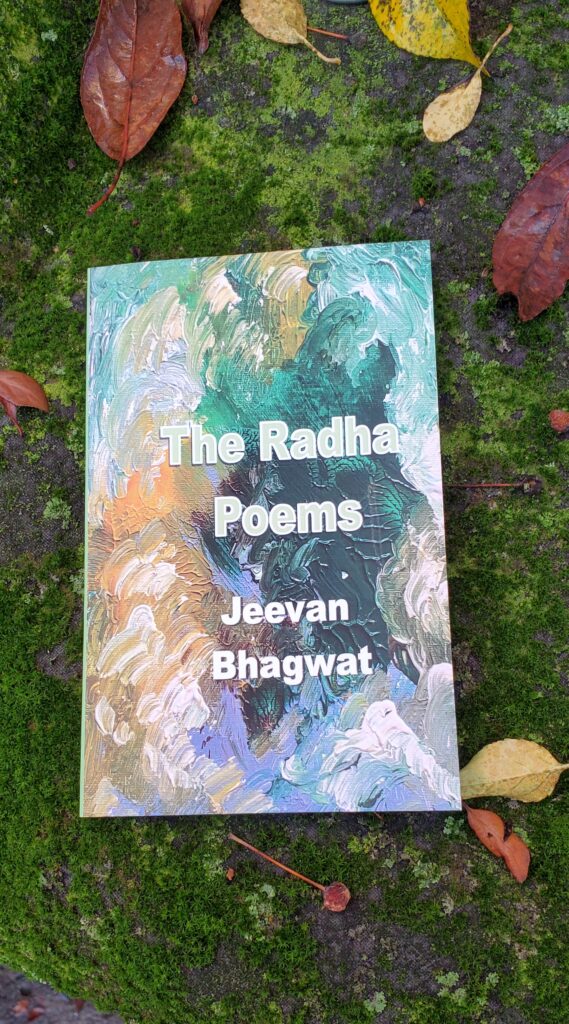 Poetry collection The Radha Poems by Jeevan Bhagwat (Silver Bow Publishing), with its colourful abstract cover, sits on a surface covered with bright green moss and some yellow and red leaves