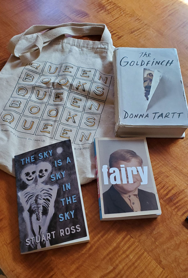 Silent book club member Vicki (me) packs her Queen Books book bag with books by Donna Tartt, Kirby and Stuart Ross to take to a silent book club meeting (Photo by Vicki Ziegler)